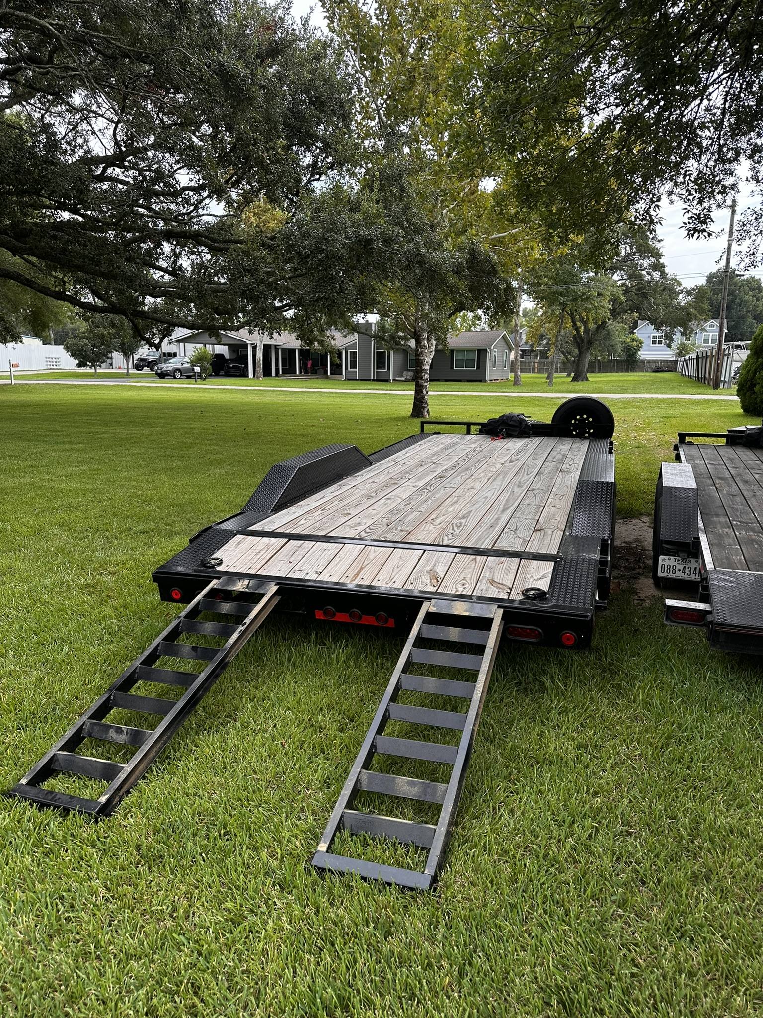 Flatbed car hauler trailer with wooden deck and loading ramps